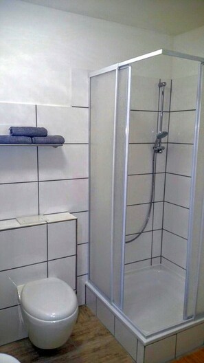 Un baño con inodoro, cabina de ducha y toallero.