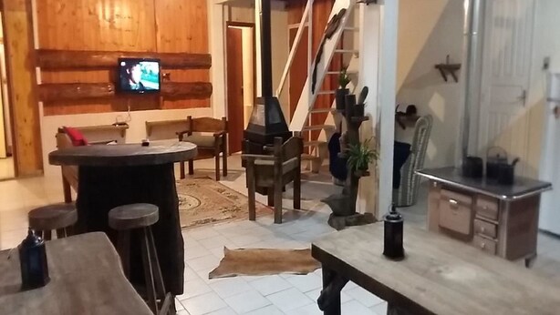 A cozy room with a wooden bar area, a staircase, and a television mounted on the wall.
