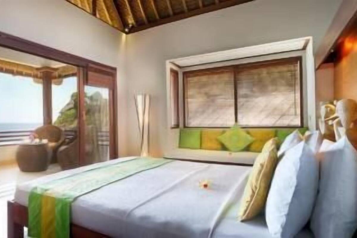Une chambre à coucher avec un lit, une fenêtre et une vue sur l’océan.