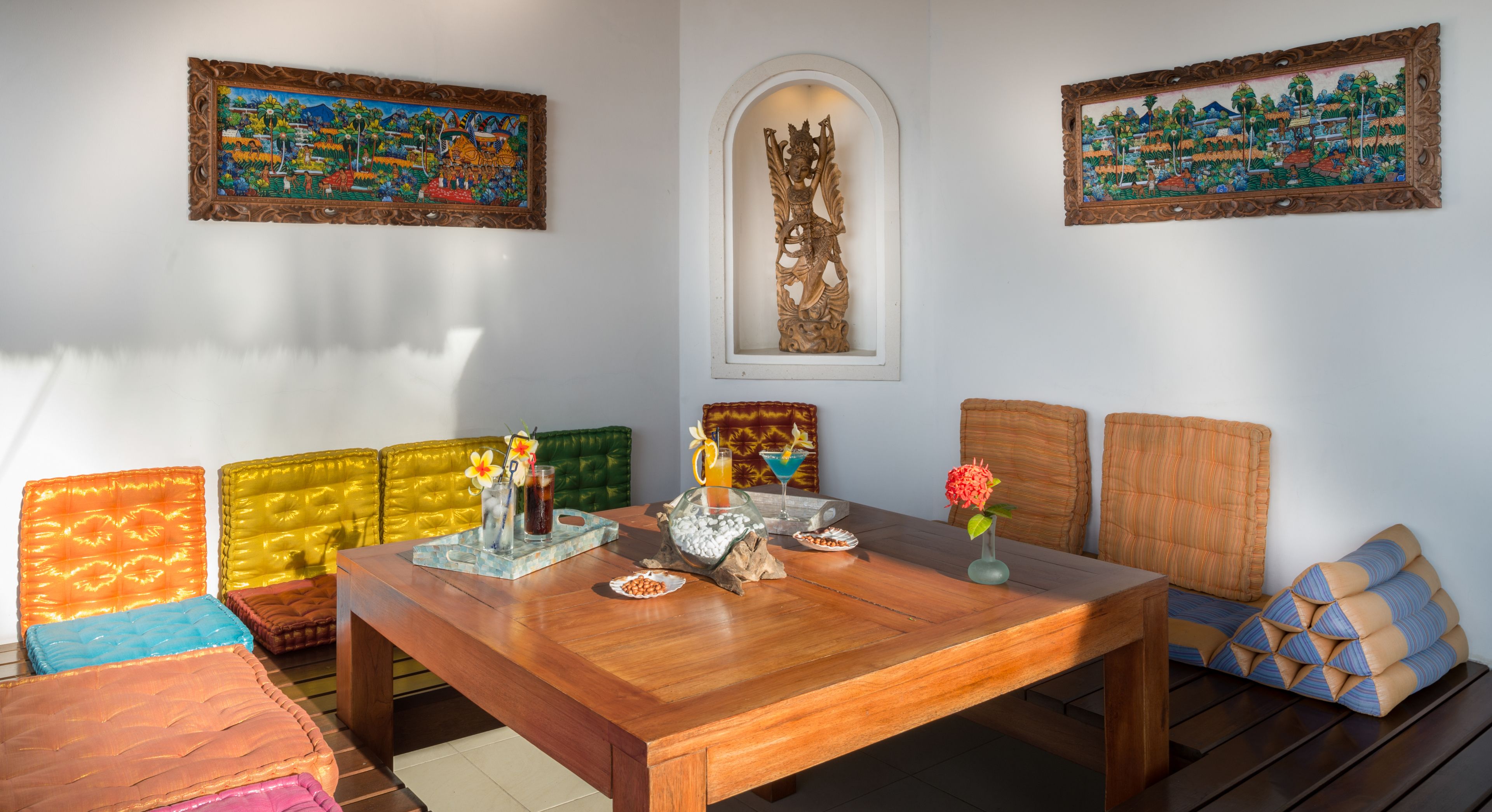 A dining area with a wooden table, colorful cushioned seating, and decorative items.