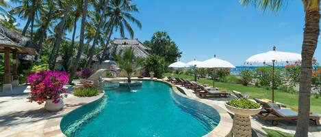 Una piscina al aire libre, sombrillas, sillones reclinables de piscina