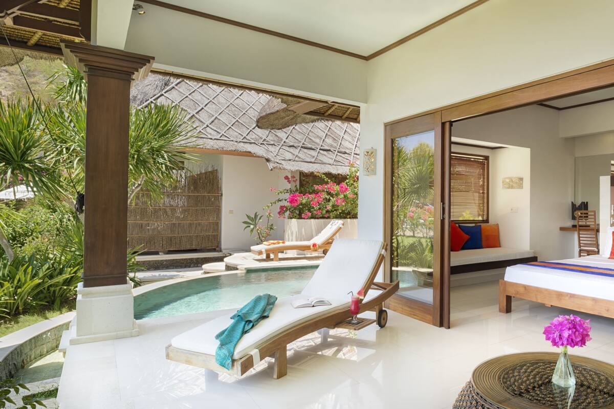 Une chambre d’hôtel moderne avec une piscine, un lit et un balcon donnant sur la piscine.