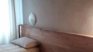 Une chambre d’hôtel avec deux lits, une tête de lit en bois, une table de chevet et une fenêtre avec des rideaux.