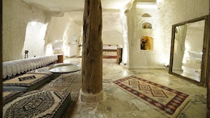 Um interior acolhedor com soalho de pedra, um pilar de madeira, um tapete estampado e um espelho grande.