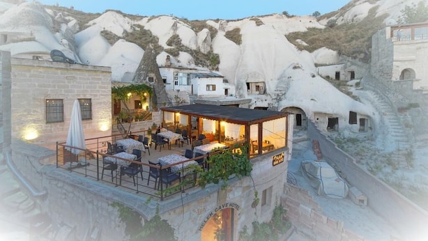 Um hotel em uma gruta com área de estar externa e vista para a paisagem rochosa ao redor.