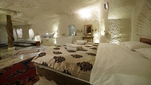 Um quarto aconchegante e bem iluminado, com uma cama grande, cabeceira de madeira, um espelho e uma mesinha com abajur.