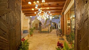 A courtyard with a wooden ceiling, hanging lanterns, potted plants, and a bench. - Melek Cave Hotel (Nevsehir)