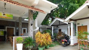 A restaurant with outdoor seating, potted plants, and a scooter parked outside. - The Bavarian Resort (Arugam Bay)