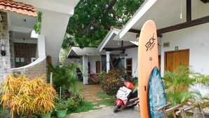 A courtyard with potted plants, a scooter, and a surfboard leaning against a wall. - The Bavarian Resort (Arugam Bay)