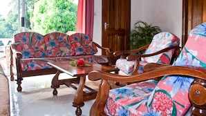 A room with a wooden sofa set, a wooden table, and a wooden door. - Villa de Roses (Mahé Island)