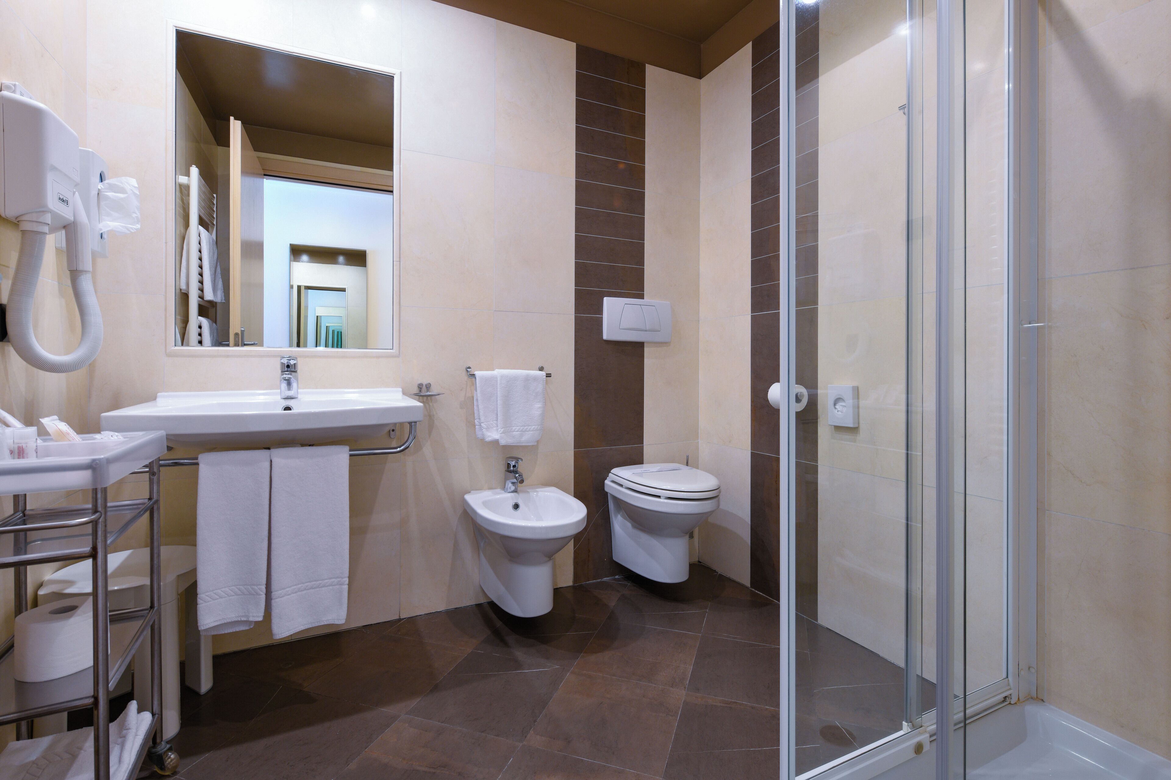 A modern bathroom with a sink, bidet, toilet, and a glass-enclosed shower.