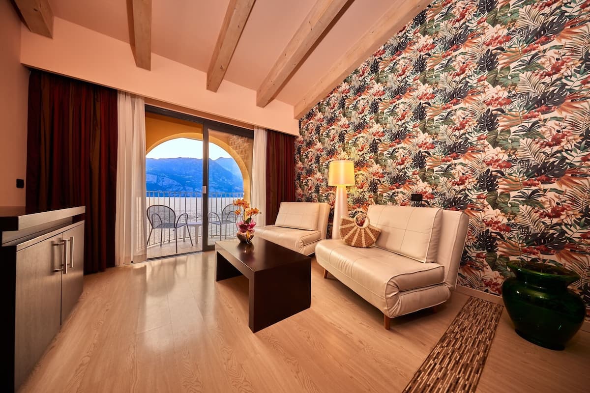 Un salon moderne avec un canapé, une table basse et une vue sur les montagnes, visible à travers une porte vitrée.
