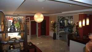En hotellobby med en stor lysekrone, en reception og en statue på en hylde.