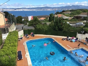 Una piscina al aire libre de temporada, sombrillas, tumbonas