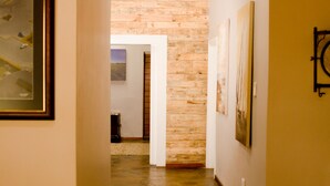 Un couloir doté d’un plancher en bois, d’un mur en briques et d’œuvres d’art encadrées qui ornent les murs.