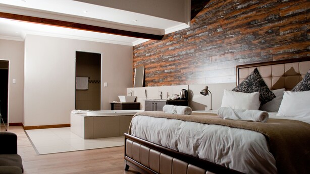 Une chambre d’hôtel moderne avec un grand lit, un petit coin salon et une salle de bain.