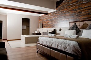 A modern hotel room with a large bed, a small sitting area, and a bathroom. - Hotel at Secunda (Secunda)