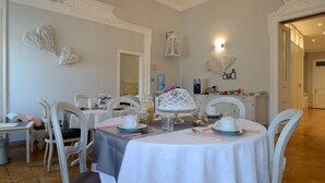 A dining area with round tables, white chairs, and a kitchen in the background. - B&B Le Cupole di Trieste (Trieste)