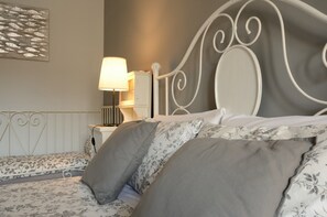 A neatly made bed with floral bedding, a bedside lamp, and a wall-mounted radiator. - B&B Le Cupole di Trieste (Trieste)