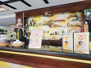 Un comptoir de café avec un tableau affichant le menu, divers produits à base de café et de thé, ainsi que des objets de décoration.