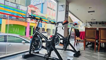 An indoor cycling area with stationary bikes, a car parked outside, and a view of colorful buildings.