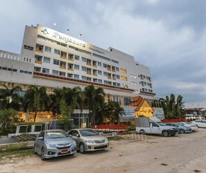 Un edificio de varios pisos con el nombre 'Punjabara' en la fachada, rodeado de coches estacionados y palmeras.