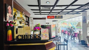 A cafe with a counter displaying 'CHEERS' and a 'CAFE' sign above. There are chairs and tables in the seating area.