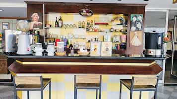 Een bar met een geruit aanrecht, barstoelen en diverse flessen en glazen.