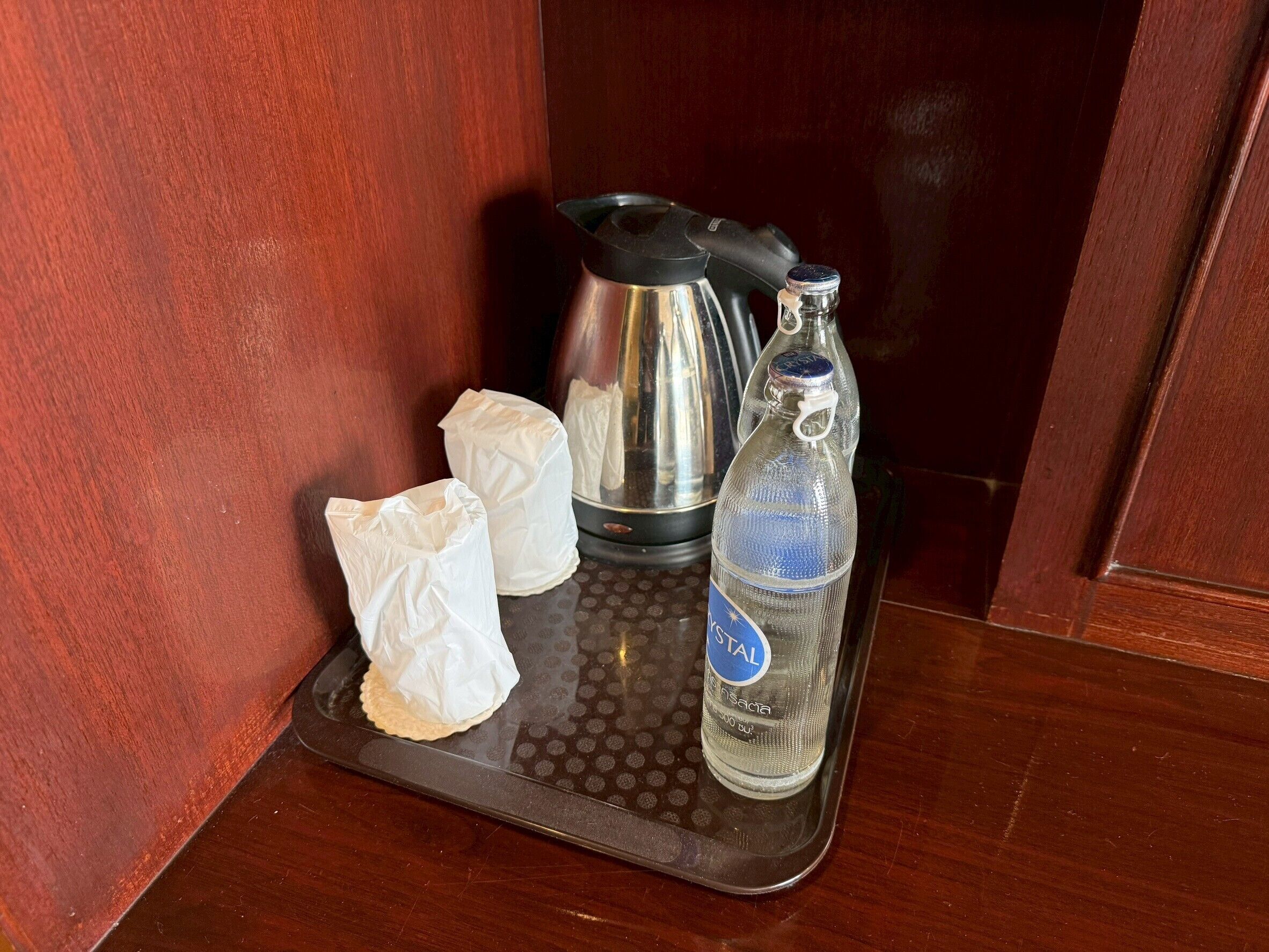 Una bandeja con una botella de agua, dos servilletas blancas y una cafetera negra.