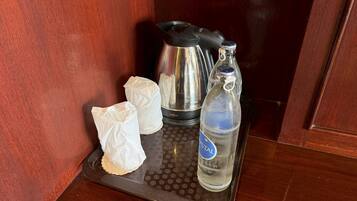 Una bandeja con una botella de agua, dos servilletas blancas y una cafetera negra.