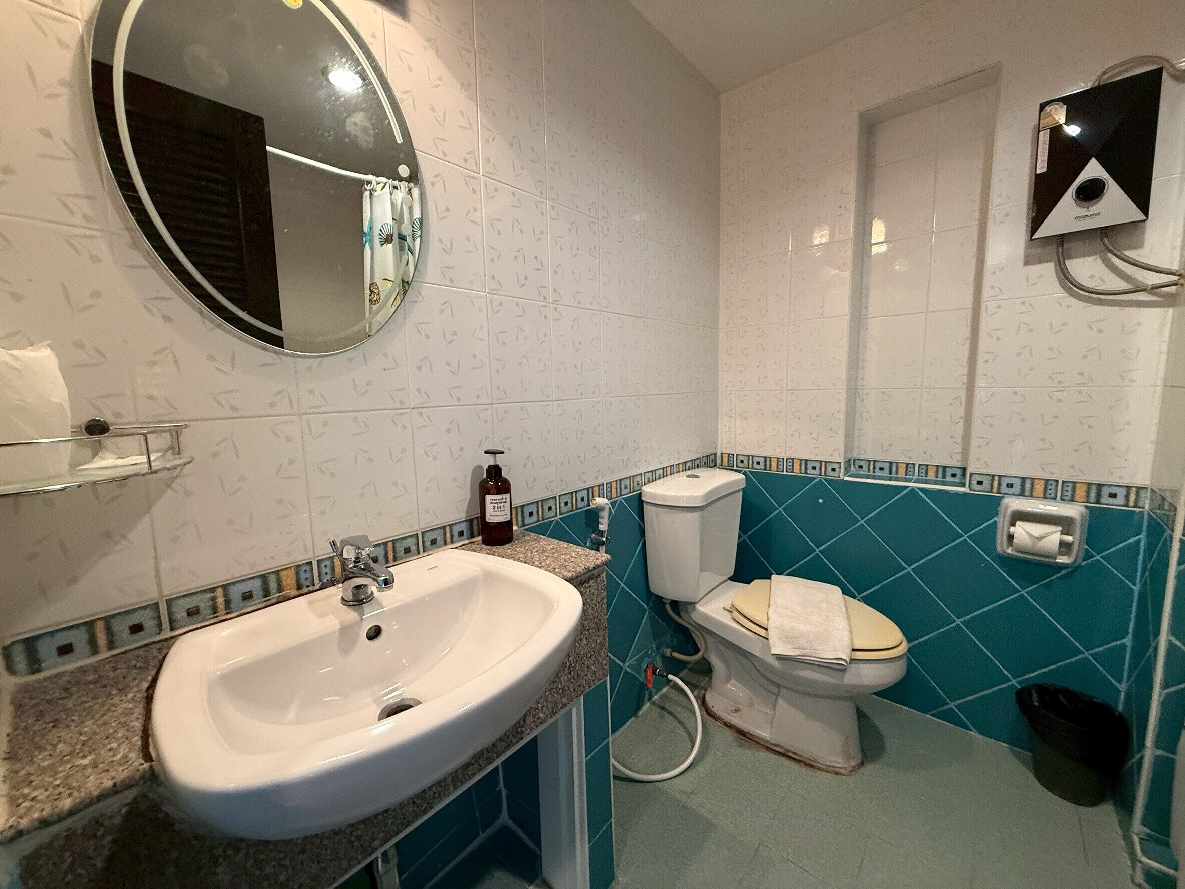 A bathroom with a sink, toilet, and mirror.