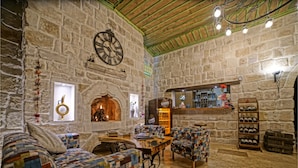Une pièce chaleureuse avec des murs en pierre, une cheminée, une horloge et un coin bar.
