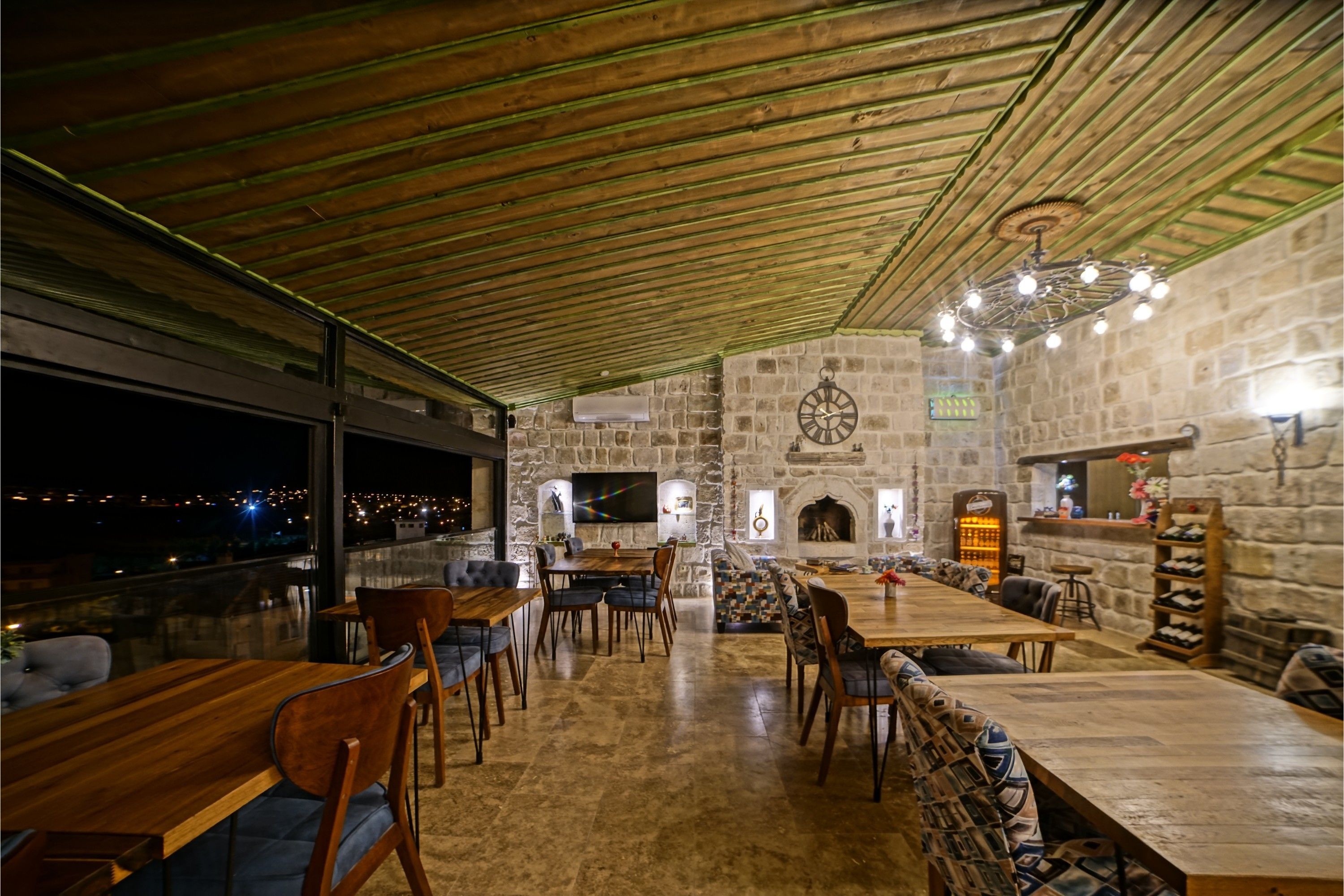 Un restaurant chaleureux aux murs de pierre, au mobilier en bois et à la grande fenêtre donnant sur la ville.