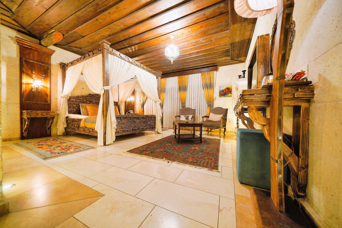 Une chambre traditionnelle avec un lit à baldaquin, un plafond en bois et une cheminée en pierre.