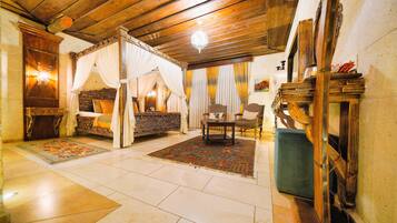 Una habitación tradicional con cama con dosel, techo de madera y chimenea de piedra.