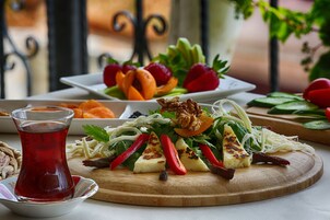 A wooden table with a variety of dishes, including a salad with vegetables and nuts, a plate of sliced fruits, and a glass of red drink.