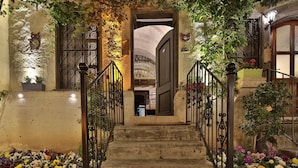 Un escalier avec des rampes en fer forgé menant à une porte surmontée d’un arc décoratif.