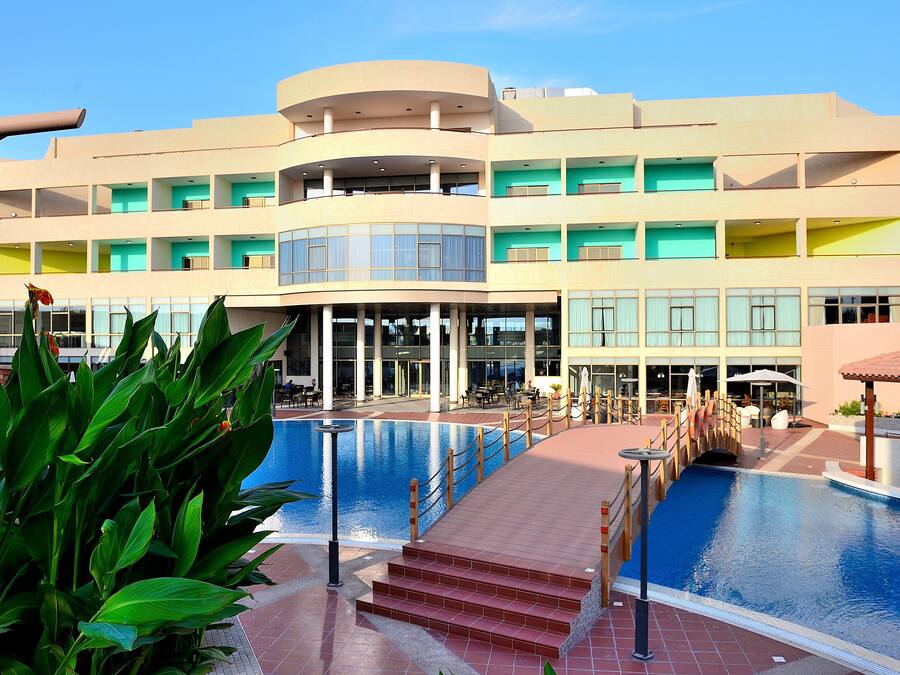 Un hotel con piscina, varios balcones y una zona exterior cubierta.