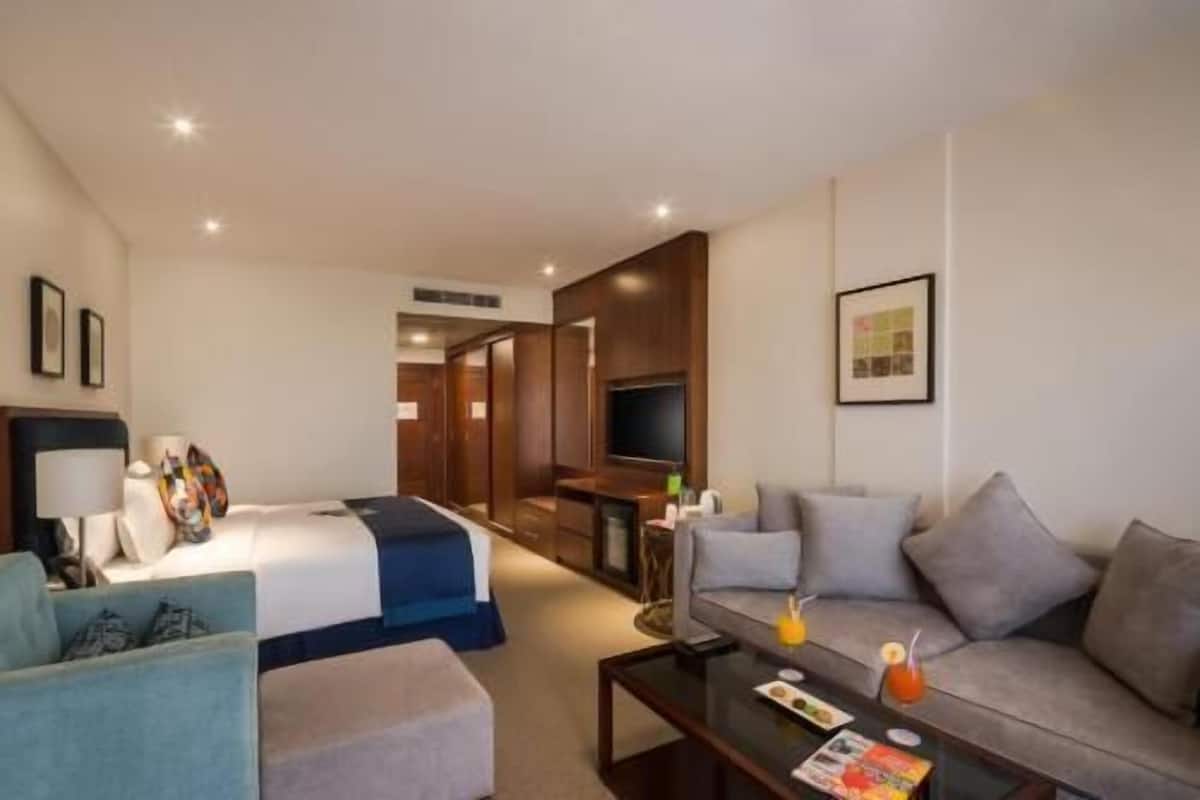 Ett hotellrum med en säng, en soffa, ett soffbord och en tv.