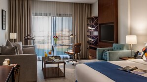 Una habitación de hotel moderna con una cama grande, un sofá, una mesa de centro, un escritorio y un televisor.