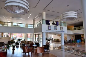 A spacious lobby with high ceilings, a central staircase, and multiple seating areas. - Al Reem Village Hotel (Al Jubail)