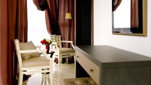 Een kamer met een kaptafel, twee stoelen, een spiegel en een lamp.
