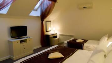 A hotel room with two beds, a TV, a desk, and a mirror.