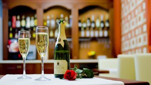 Een barsetting met twee champagneglazen, een wijnfles en een roos op een tafel.