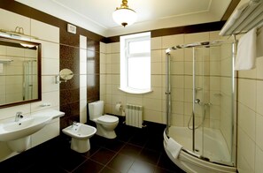 A bathroom with a sink, bidet, toilet, and a glass-enclosed shower. - Villa Rossa (Chisinau)