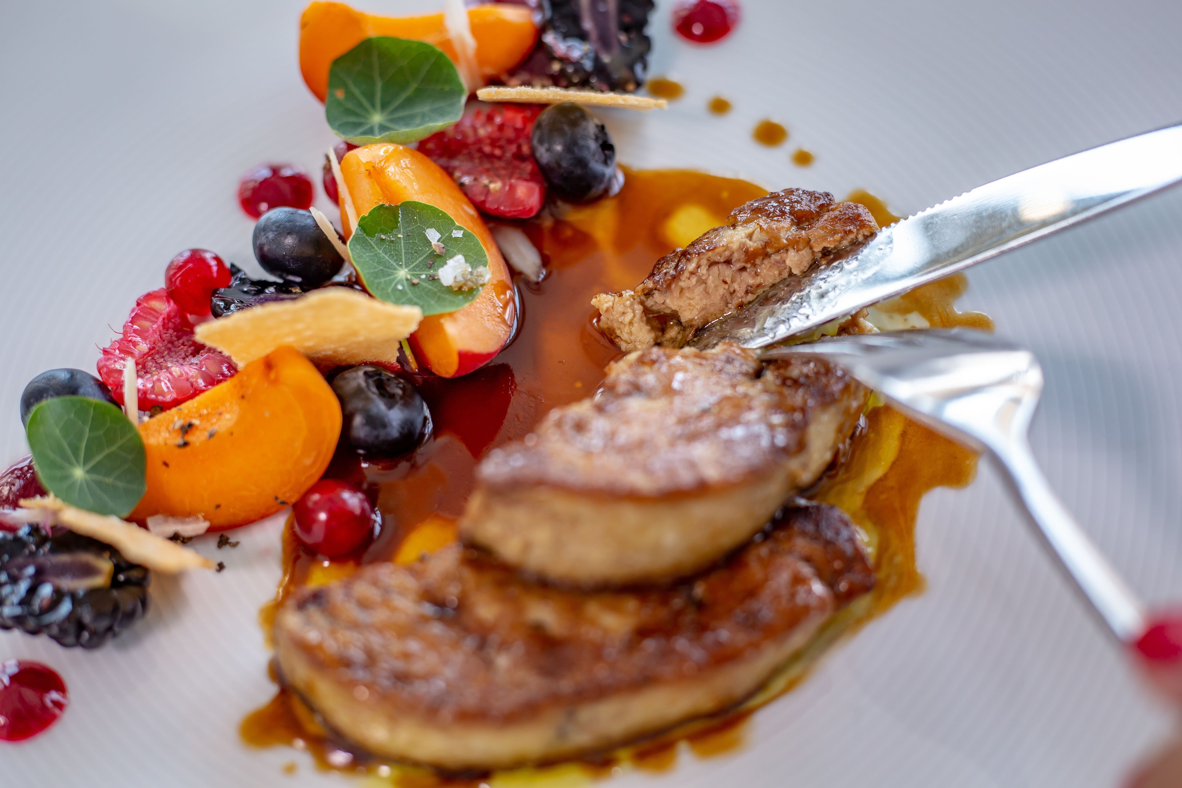 A plated dish with pancakes, berries, and a drizzle of syrup.