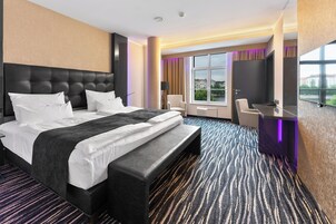 Een moderne hotelkamer met een groot bed, een bureau en een televisie.