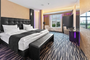 Een moderne hotelkamer met een groot bed, een bureau en een televisie.