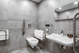 Casa de banho moderna com sanita, lavatório e chuveiro.