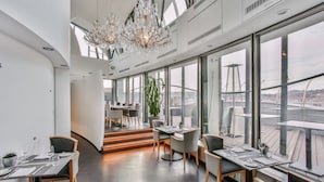 A modern restaurant with high ceilings, large windows, and a chandelier. Tables are set with plates, glasses, and cutlery. - Dancing House hotel - Tančící dům (Prague)
